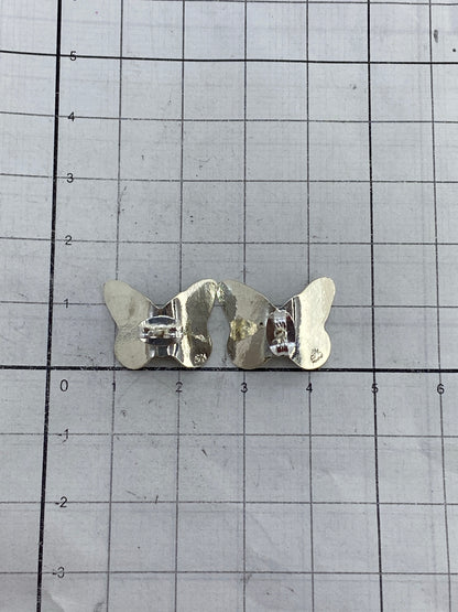 Aretes de mariposa sobre fondo gris mostrando el acabado pulido de la plata 925