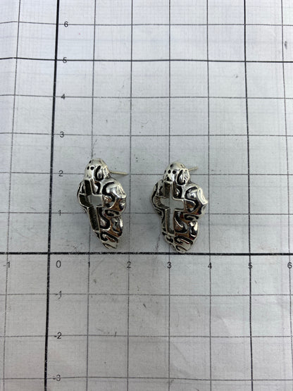 Aretes de plata religiosos sobre fondo blanco mostrando el acabado pulido
