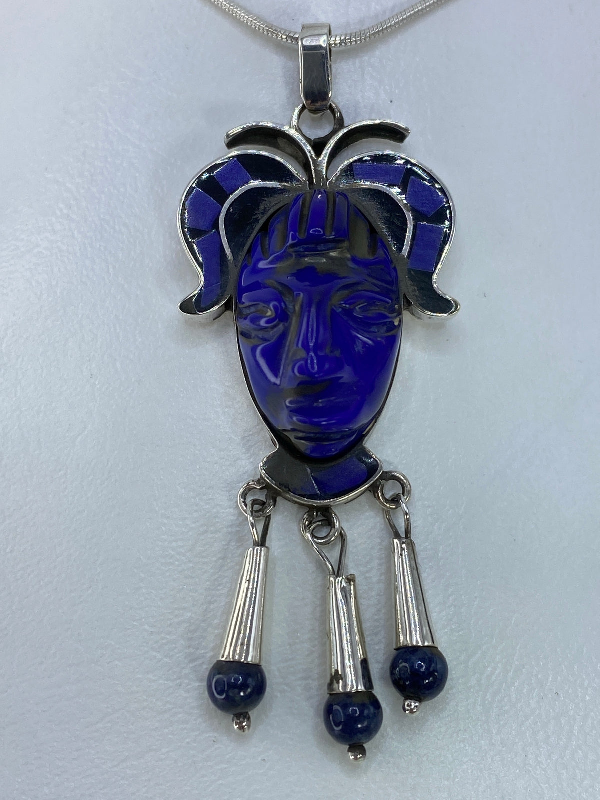 Dije máscara azul de plata 925 con piedra incrustada, colgando de cadena serpentín