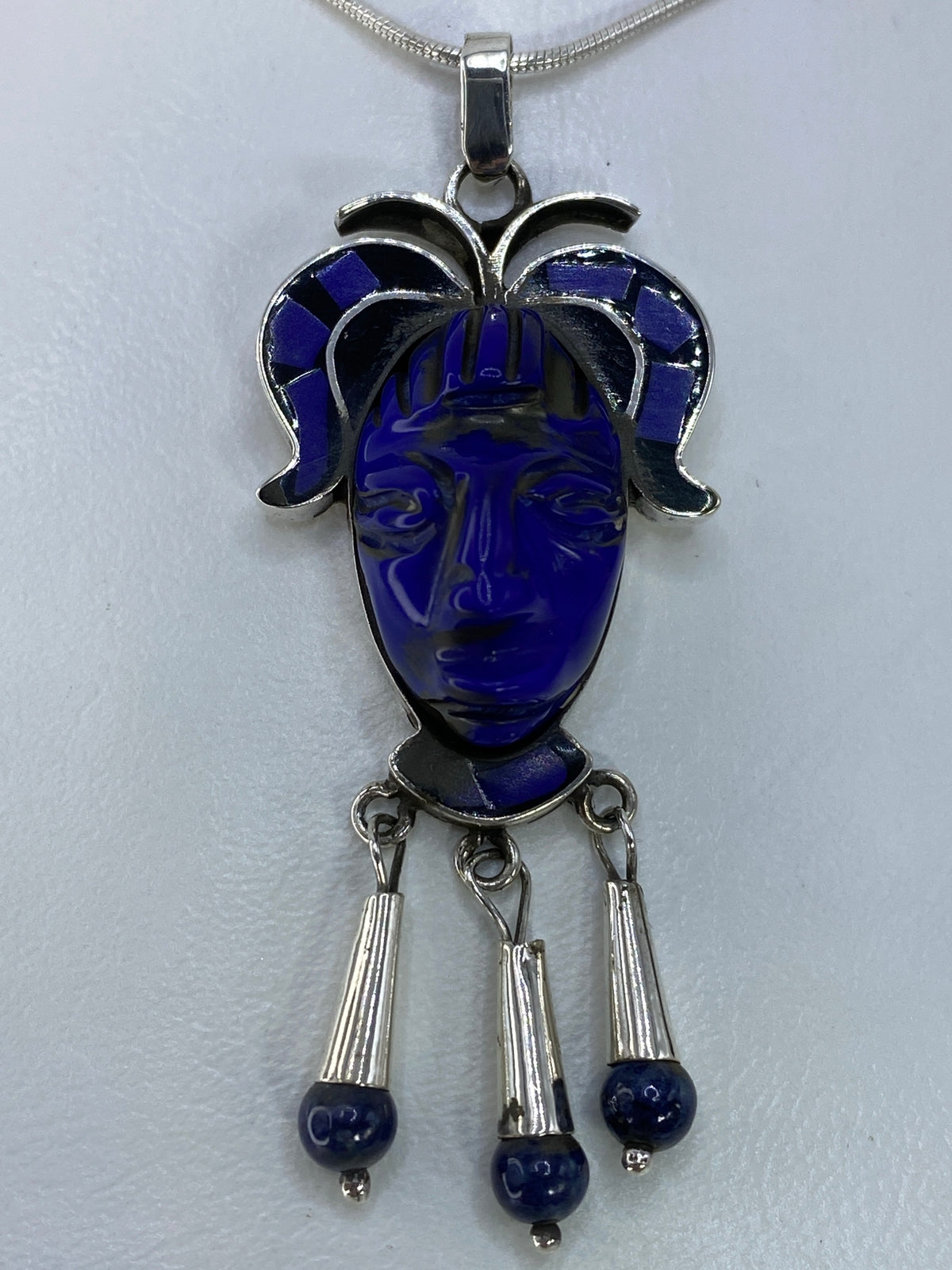 Detalle frontal del rostro tallado en plata con piedra azul engastada en la cara