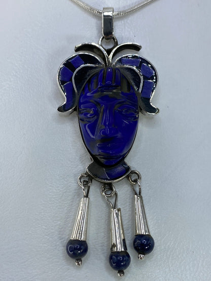 Detalle frontal del rostro tallado en plata con piedra azul engastada en la cara