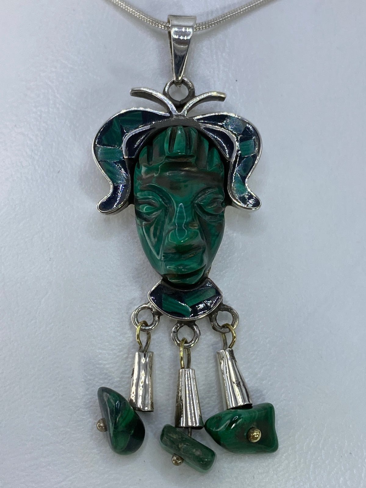 Dije de plata 925 con rostro prehispánico tallado en malaquita verde, colgado en cadena de plata