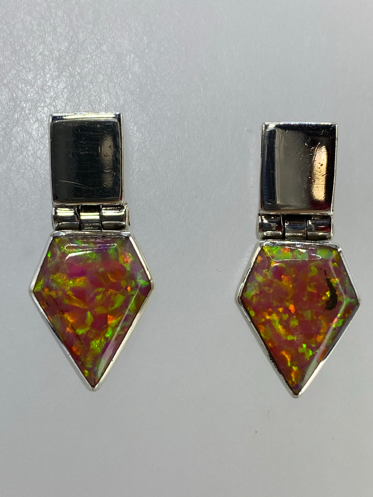 Aretes de ópalo sobre fondo azul mostrando el engaste de plata pura