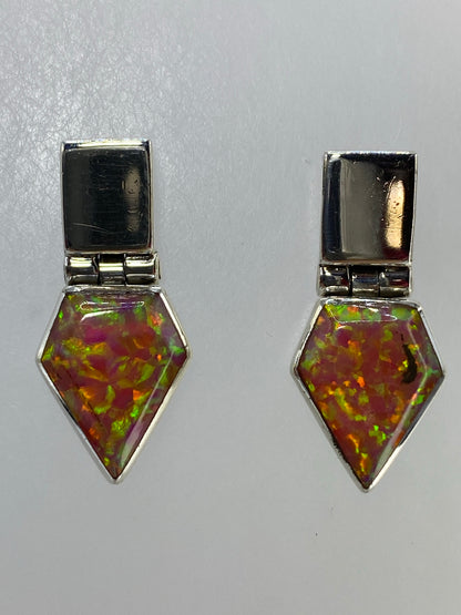 Aretes de ópalo sobre fondo azul mostrando el engaste de plata pura
