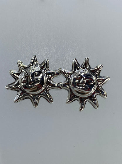 Detalle frontal de los aretes solares mostrando el volumen 3D y el pulido brillante de la plata 925