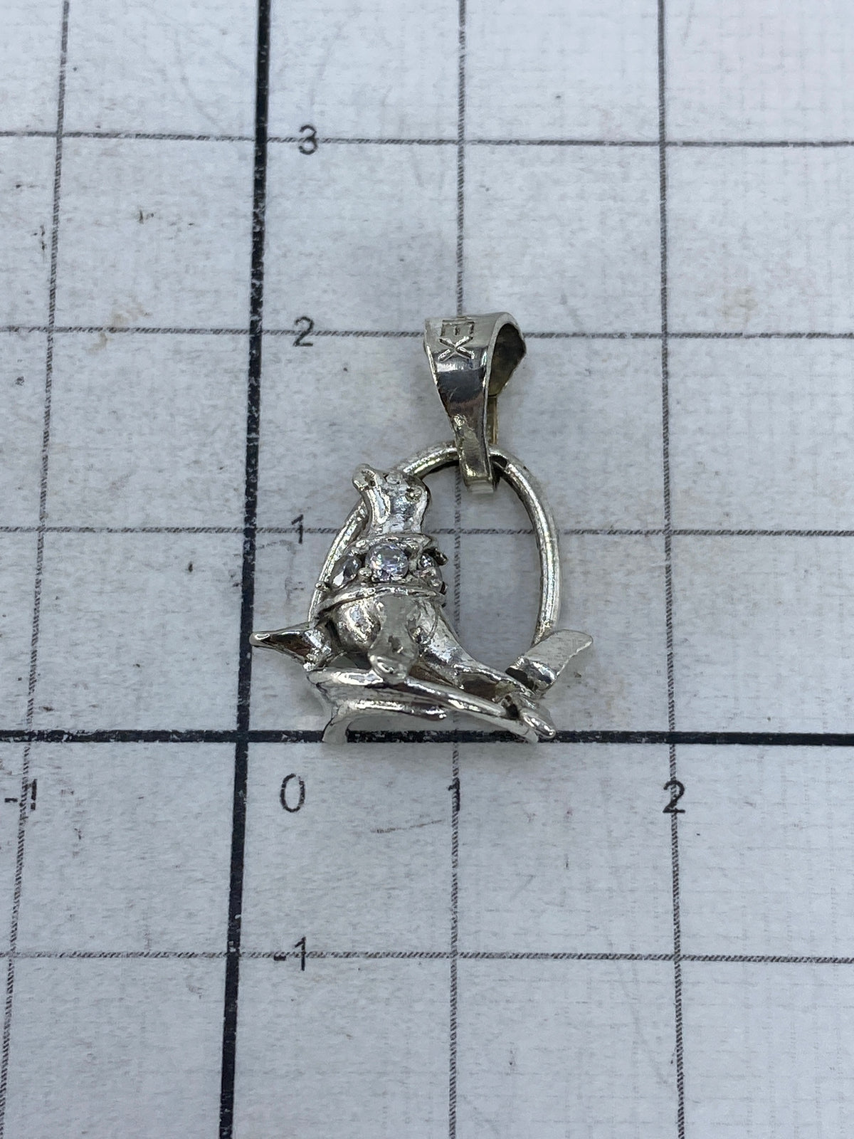 Dije sobre regla: 2.2 cm de largo, tamaño compacto de moneda