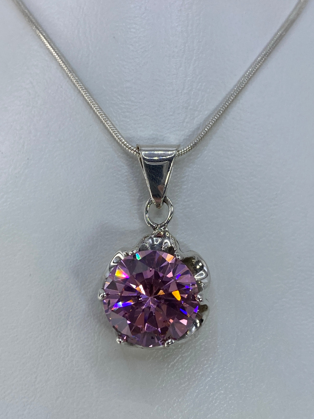 Dije de plata 925 con circonia rosa engastada, brilla en tonos azules y dorados