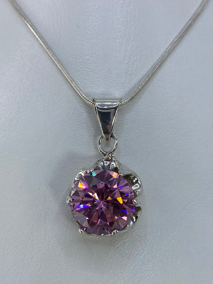 Dije de plata 925 con circonia rosa engastada, brilla en tonos azules y dorados