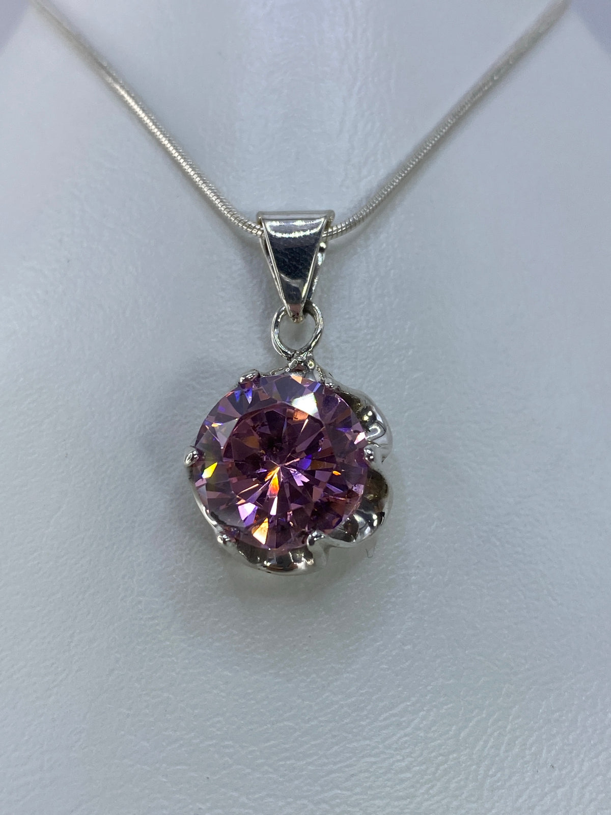 Vista frontal del dije de plata con piedra rosa, 2.8 cm de largo sobre una regla