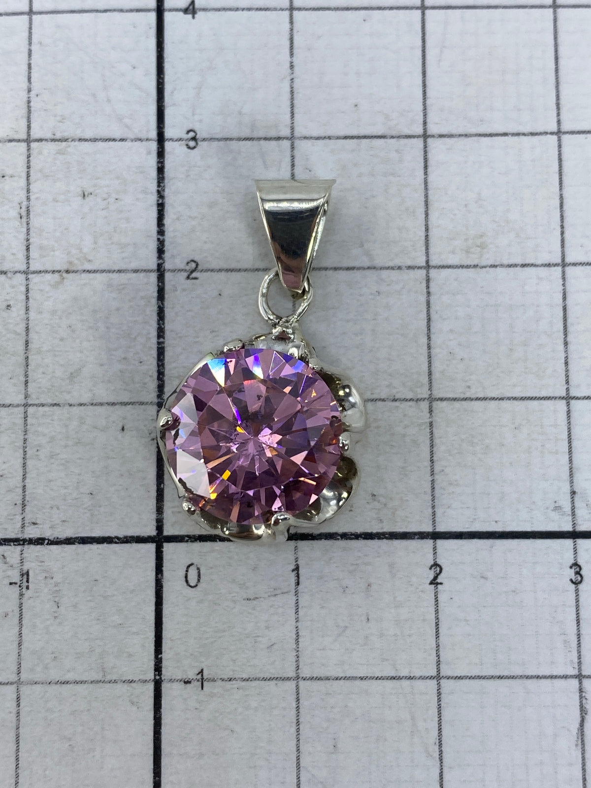 Dije de circonia rosa sobre fondo gris, mostrando el sello 925 en la base