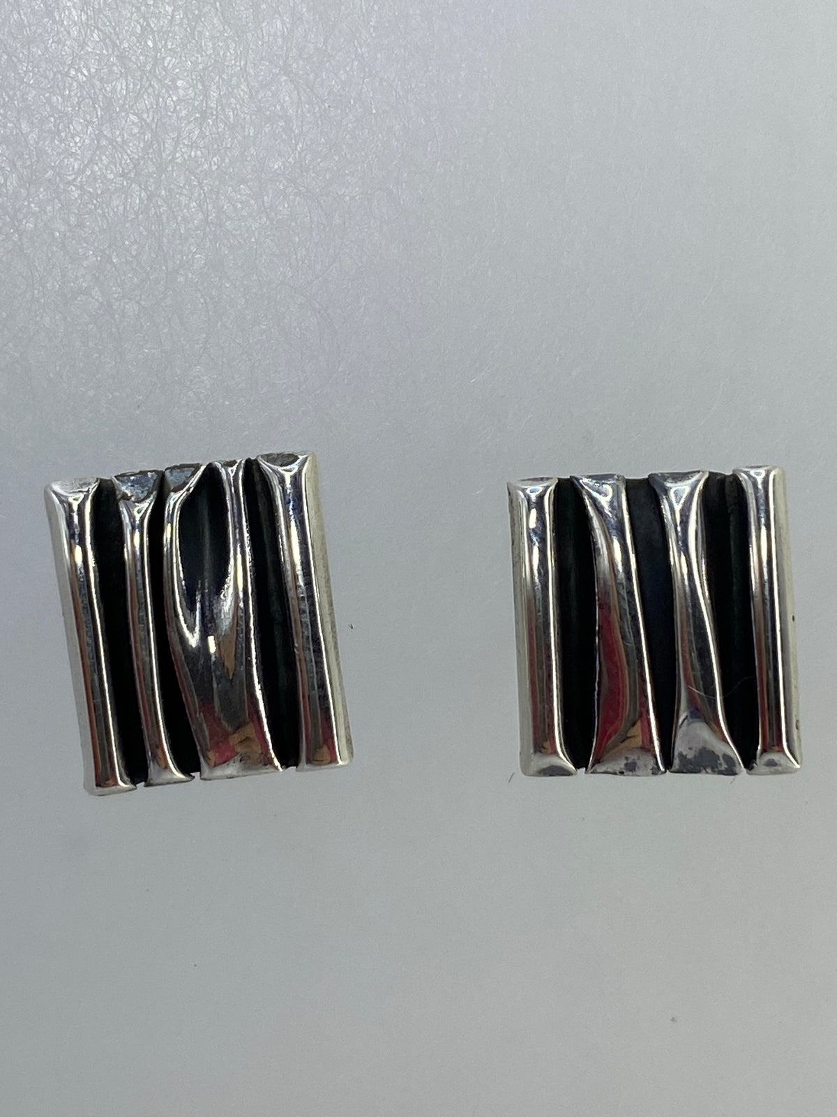Detalle del cartoneado: pliegues de plata trabajada a mano en cada arete