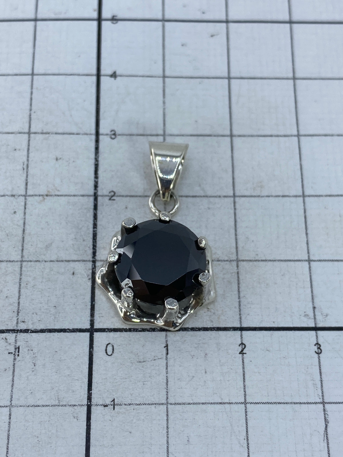 Dije sobre regla milimetrada mostrando tamaño real de 2.8 × 1.6 cm