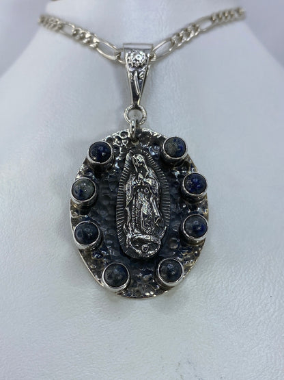 Lateral del dije religioso mostrando la profundidad del repujado y el detalle de las piedras