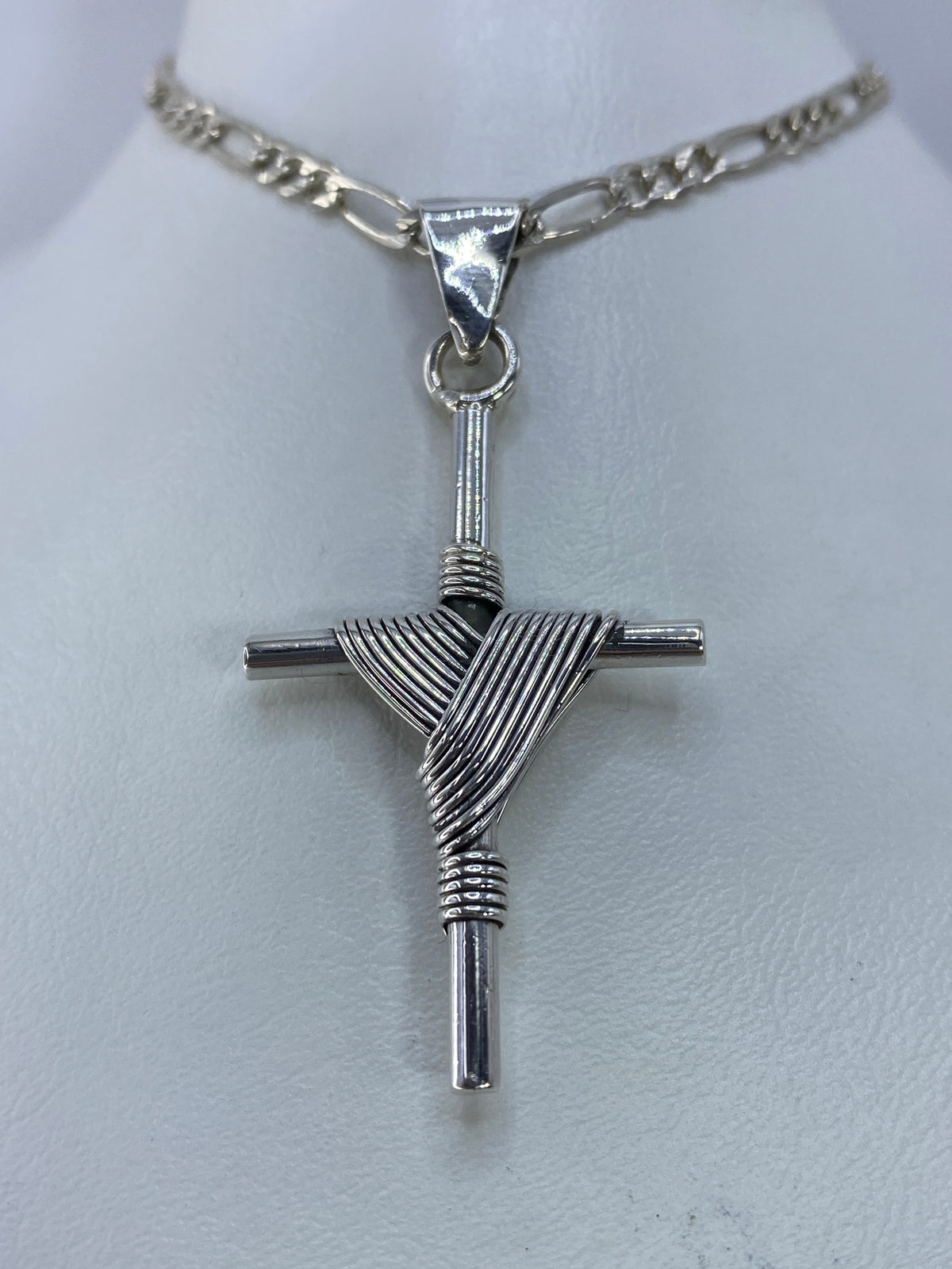 Detalle frontal de la cruz de plata mostrando el patrón de hilos y el acabado brillante