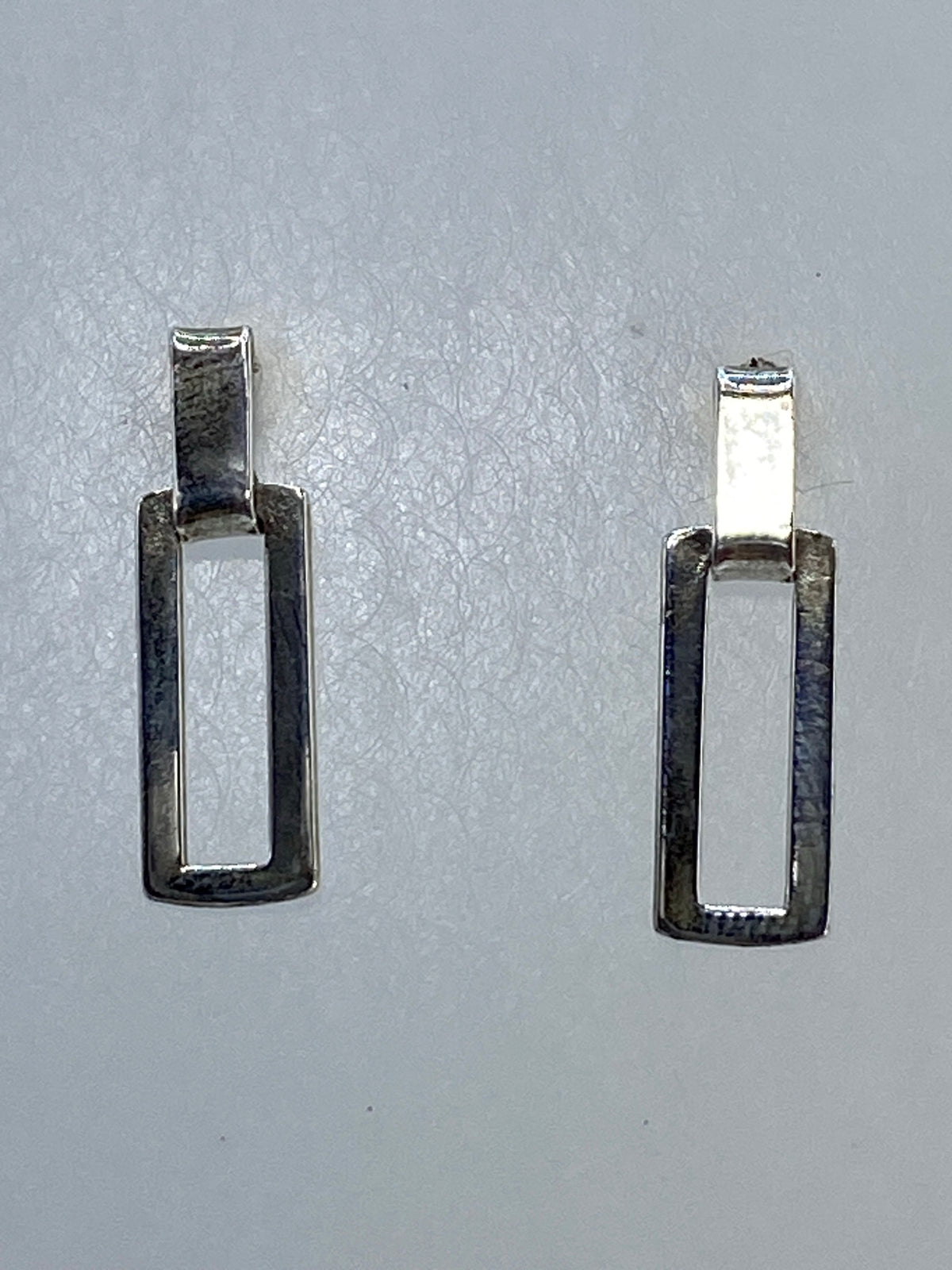 Aretes de plata calado geométrico sobre escala, mostrando 1.49 gramos