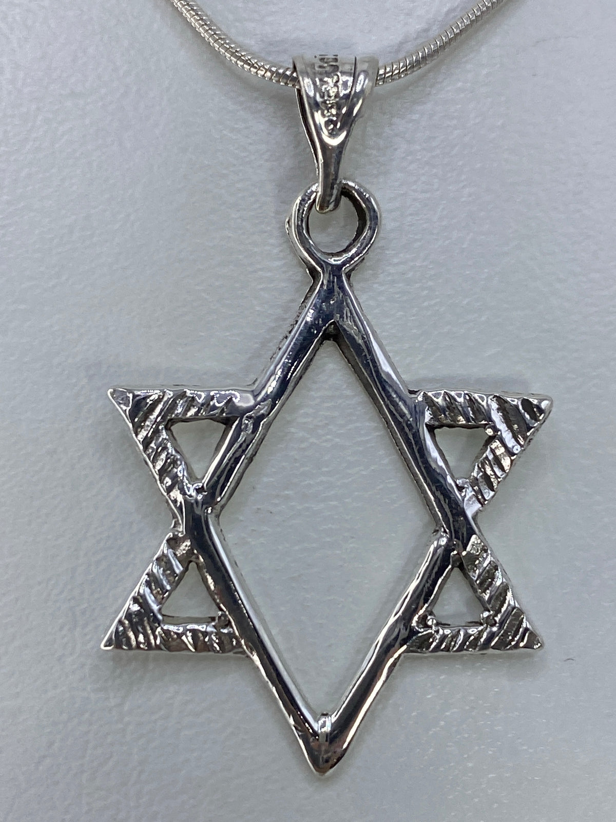 Detalle del dije Estrella de David colgando de una cadena de plata