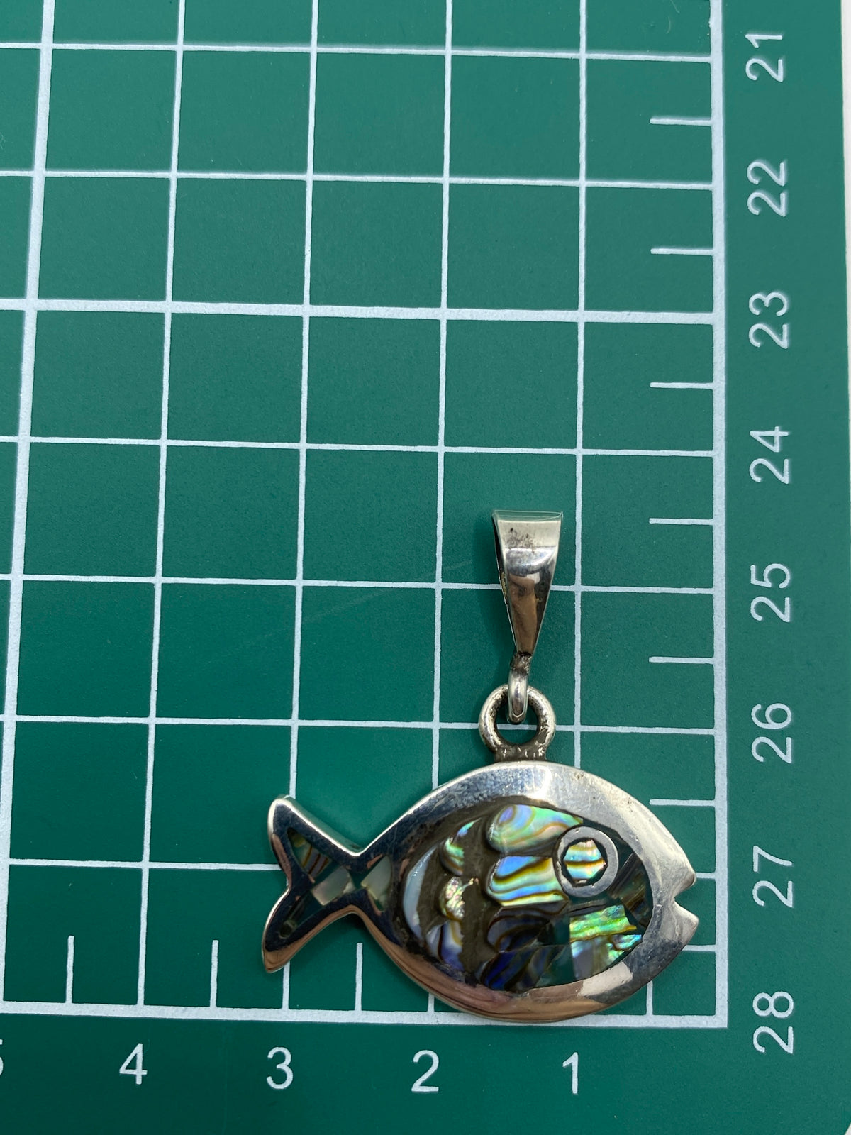 Dije de pez sobre fondo blanco con escala de medidas mostrando 3.5 cm, con marca de Quinto 950