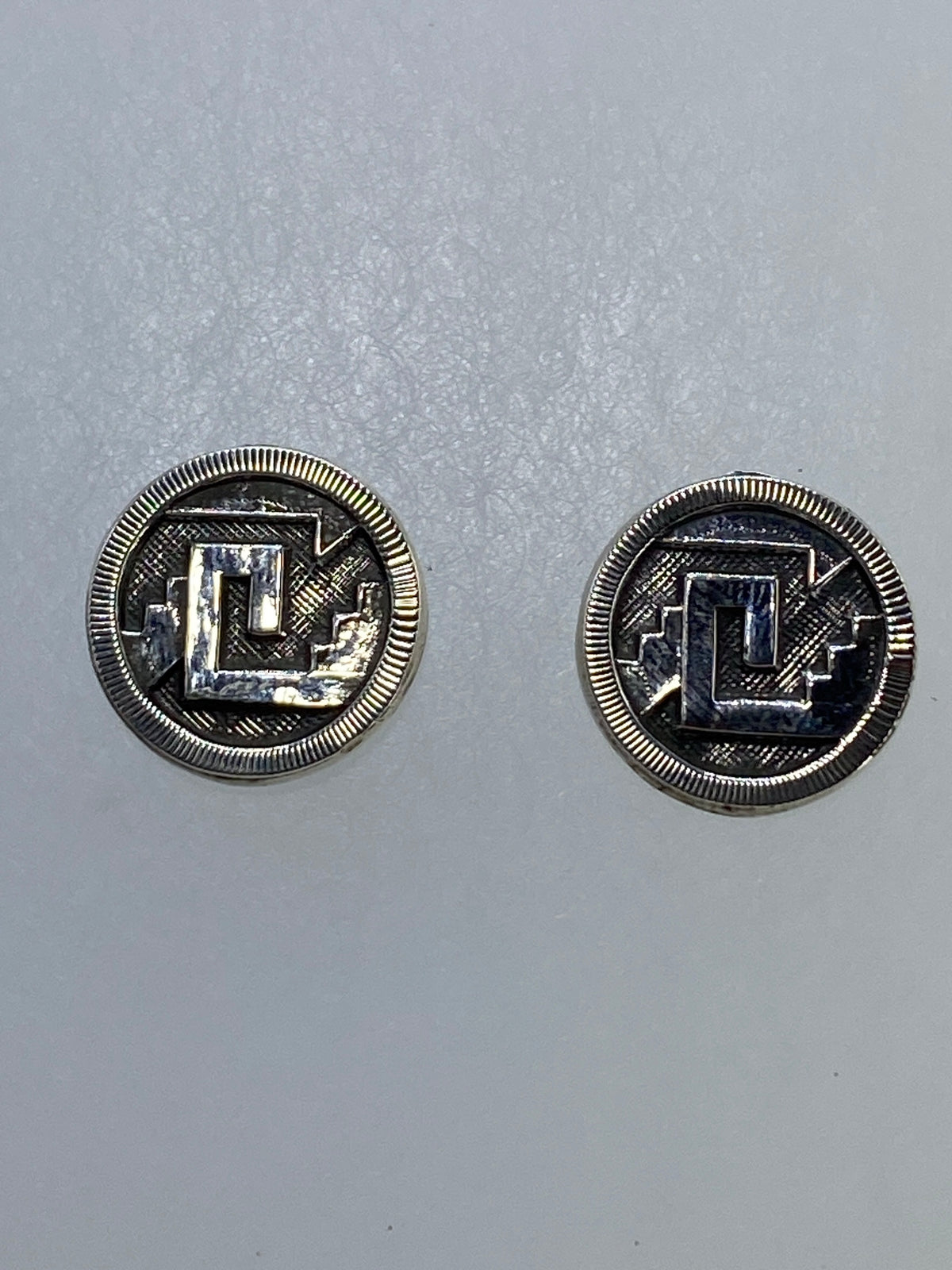 Par de aretes de plata cartoneado con motivo prehispánico geométrico, vista frontal