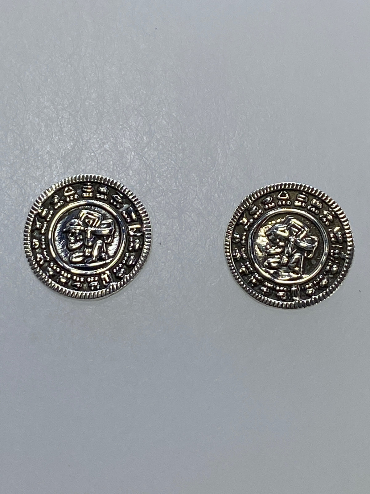 Aretes prehispánicos en cartoneado sobre fondo azul, lado frontal