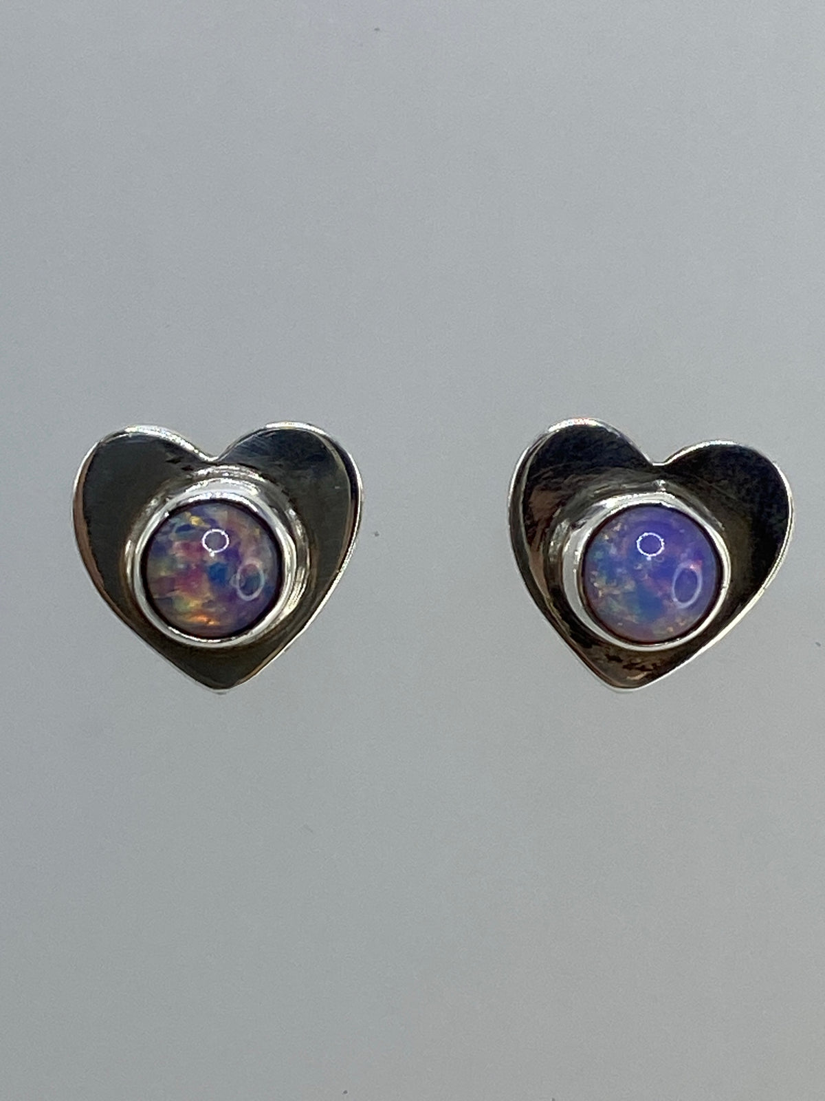 Par de aretes de plata con ópalo de fuego multicolor brillante, mostrando destellos naranja y azul