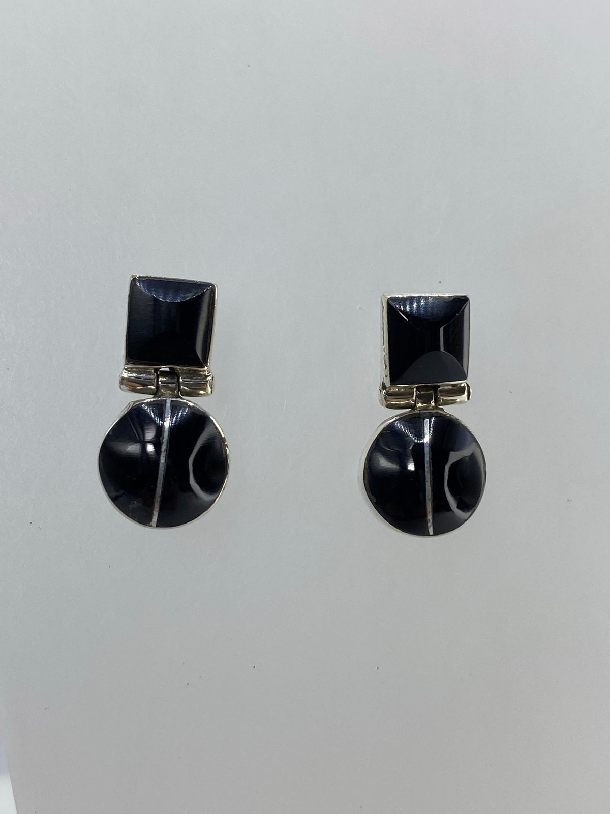Detalle lateral de arete con cuadrado de plata e incrustación de ónix negro pulido