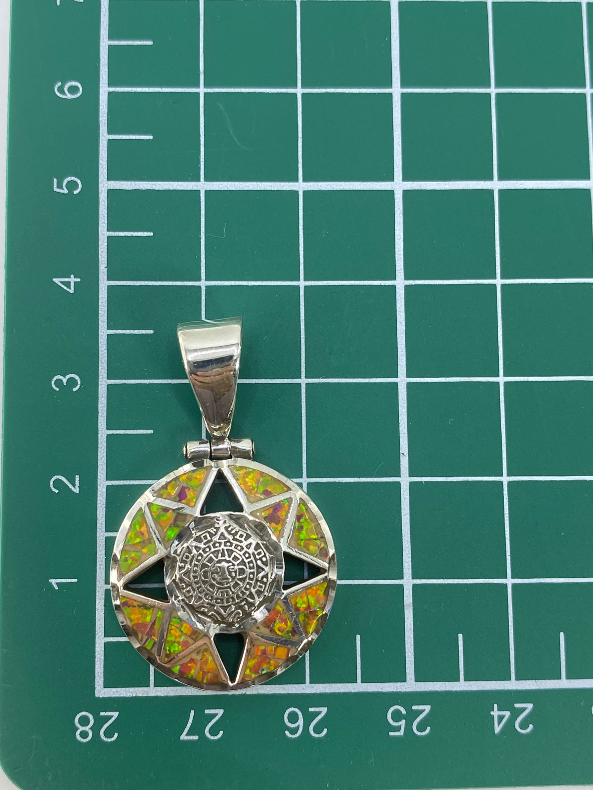 Dije Calendario Azteca de 3.5 cm sobre regla de medida — tamaño real