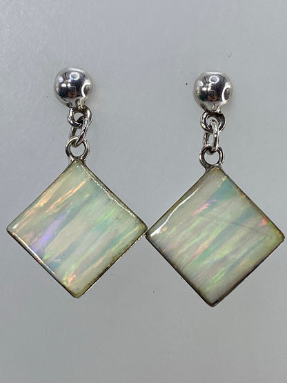 Par de aretes de plata con ópalo de fuego multicolor, visto desde arriba con iluminación neutra