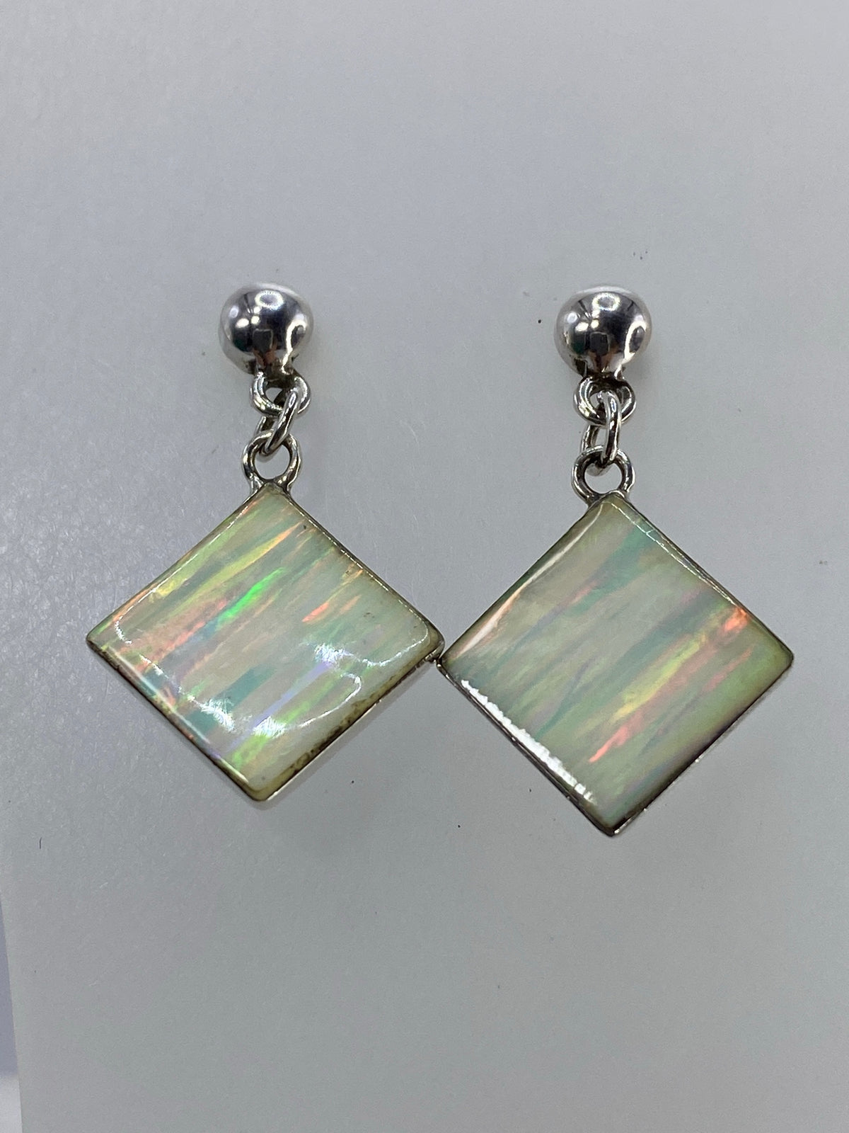 Detalle de un arete mostrando el ópalo de fuego con tonos de verde, rojo y amarillo