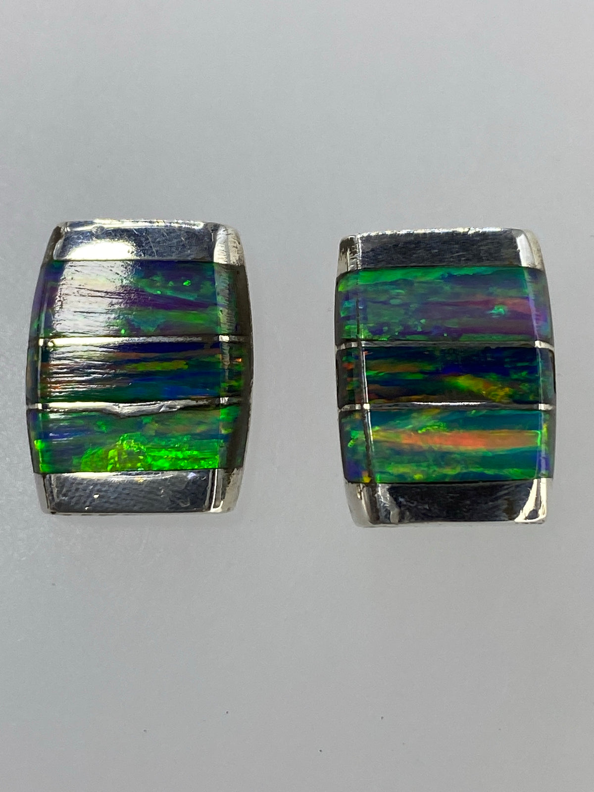 Par de aretes de plata 950 con ópalo de fuego multicolor, vista frontal mostrando los tonos naranjas, verdes y azules