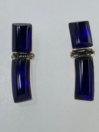 Aretes de plata sobre fondo verde de medición, mostrando tamaño real