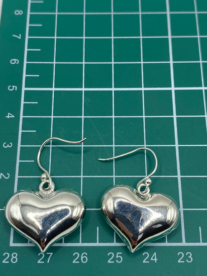 Par de aretes de corazón sobre fondo blanco con el Quinto 925 visible