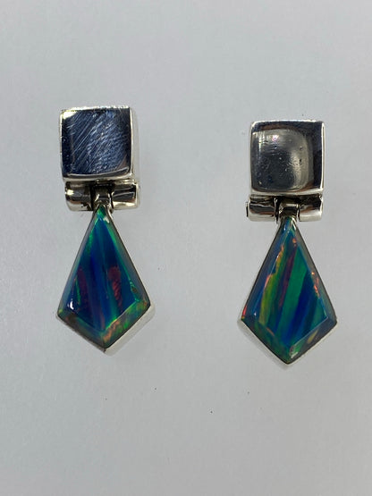 Aretes de plata 950 con ópalo de fuego multicolor facetado, par simétrico sobre fondo neutro