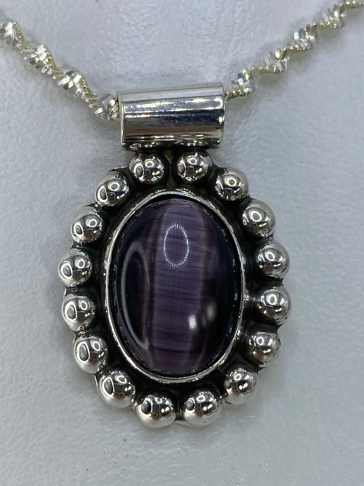 Dije de plata 925 con Ojo de Gato morada engastado a mano, colgando de cadena de eslabones