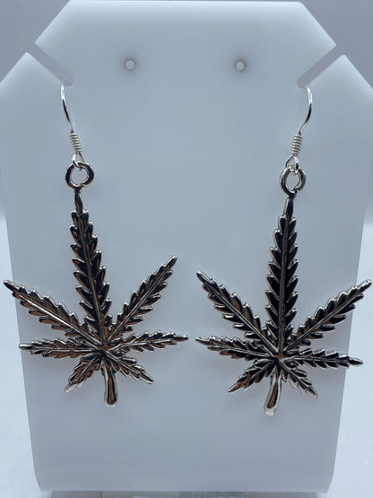 Par de aretes de plata repujada con motivo cannabis estilizado en diseño prehispánico