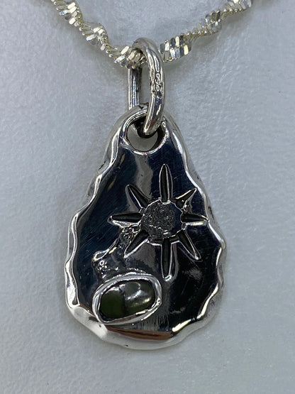Dije de plata en forma de gota con piedra verde engastada, vista frontal sobre cadena