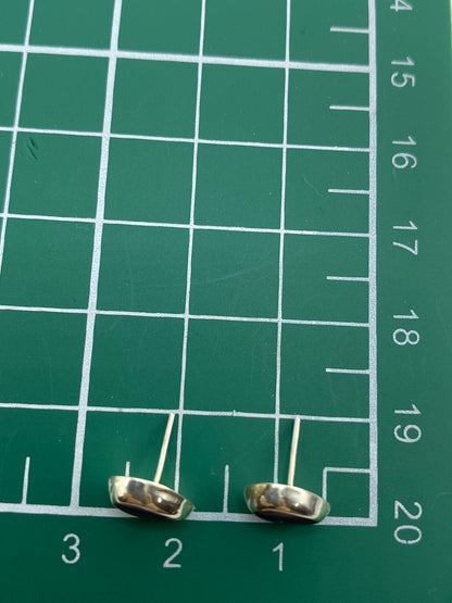 Los aretes en una balanza de precisión mostrando su peso ligero de 0.57 g