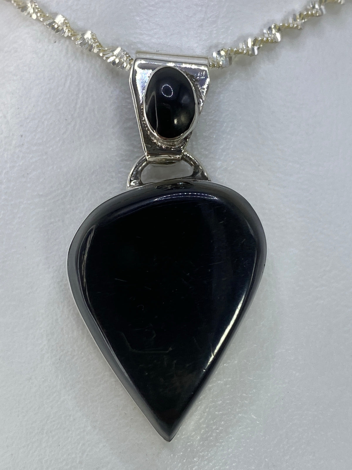 Vista frontal del dije corazón negro en plata 925 de Taxco, detalle del engaste de piedra.
