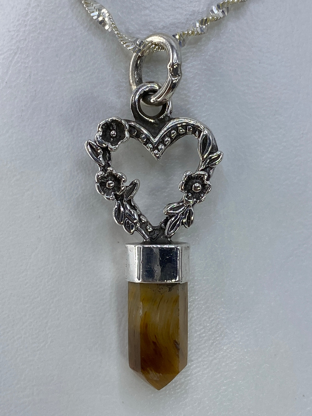 Dije de plata con cuarzo café de 4.5 cm colgando de una cadena plateada