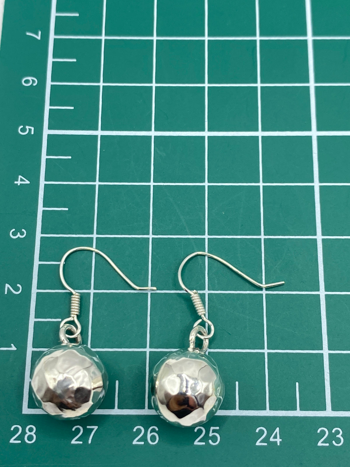 Aretes de frente, mostrando el diseño geométrico facetado y el acabado espejo