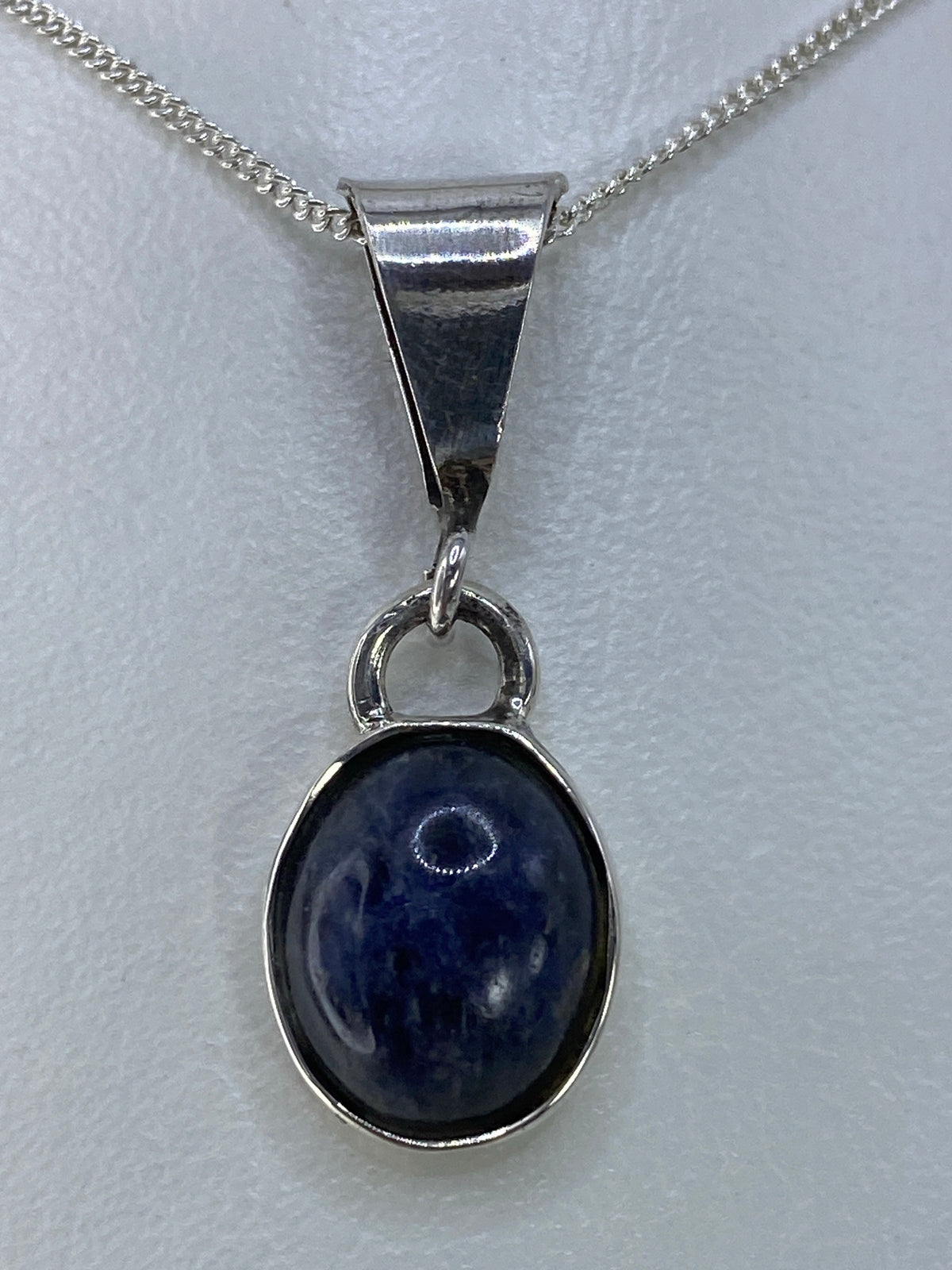 Dije de plata con piedra azul de 3 cm colgando de cadena de plata