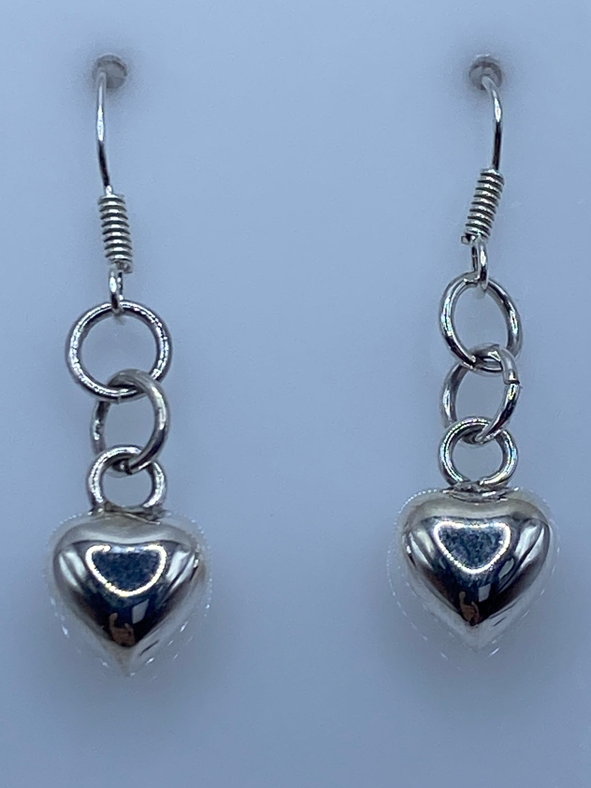 Par de aretes de plata 925 con forma de corazón cartoneado, gancho de plata, sobre fondo blanco
