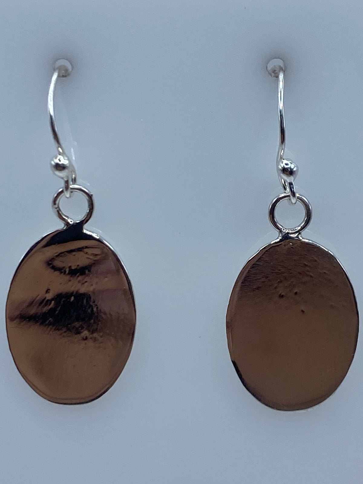 Aretes de plata ovalados sobre escala de medida mostrando largo de 3.5 cm