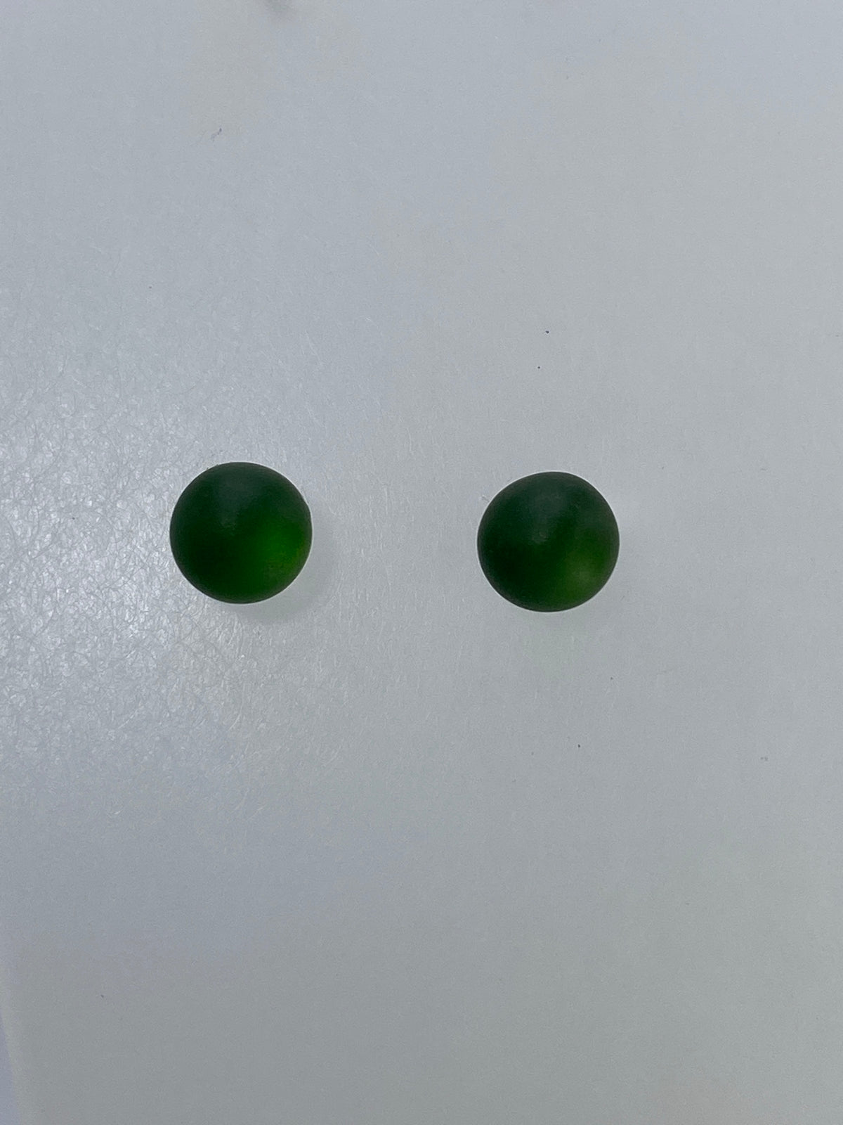 Aretes verdes con engaste de plata, mostrando el cierre de mariposa