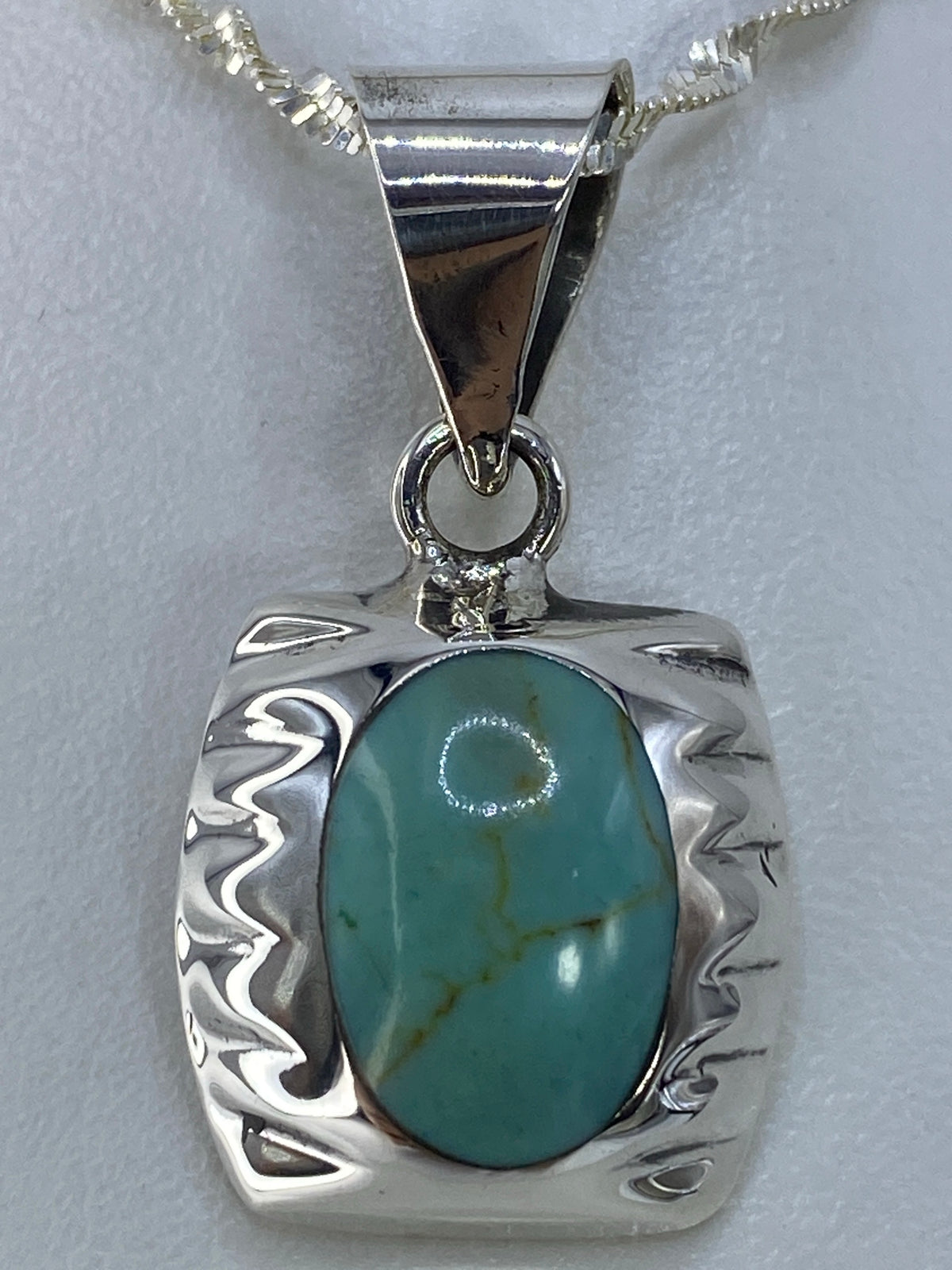 Dije de plata junto a regla para escala, midiendo 3.5 cm de largo