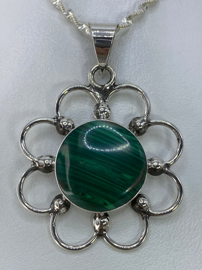 Detalle frontal del dije mostrando la piedra verde engastada a mano en plata 925