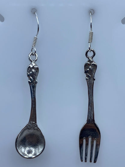 Detalle del arete con forma de tenedor mostrando los dientes definidos en plata pulida