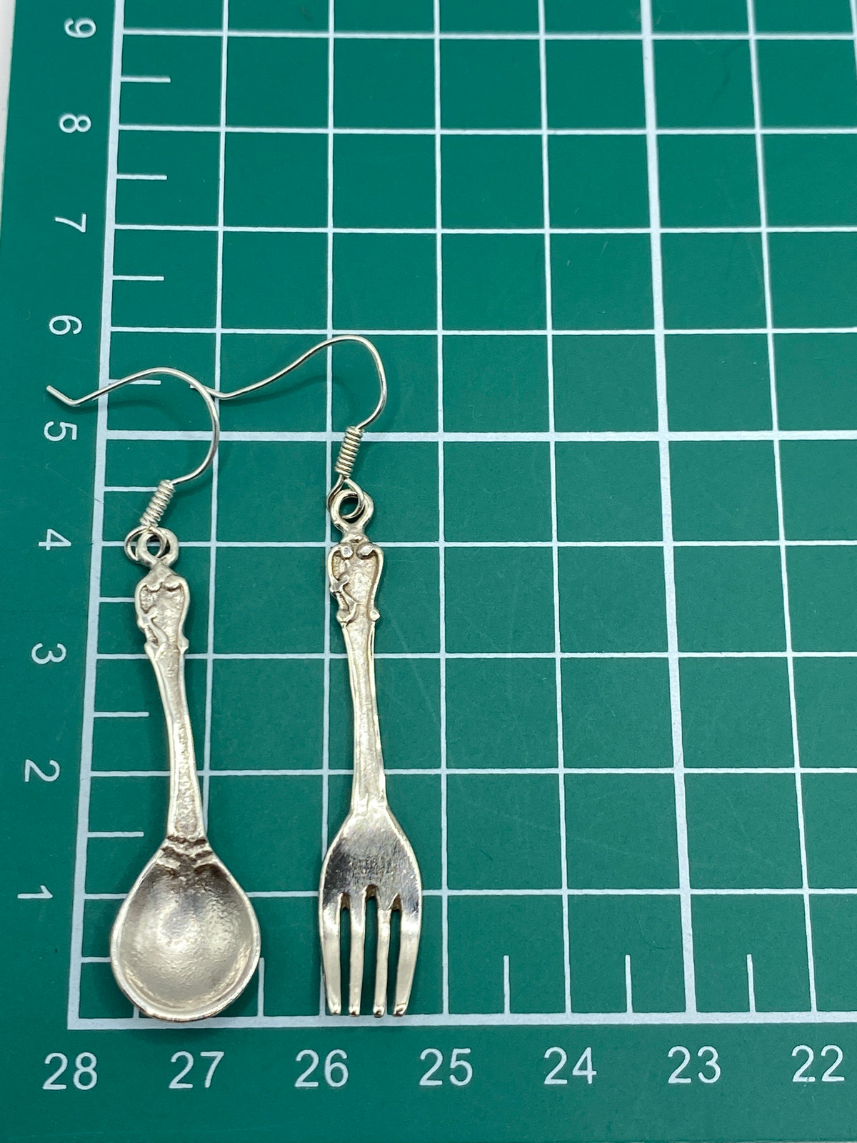 Los dos aretes juntos en palma de mano mostrando escala y ligereza del diseño