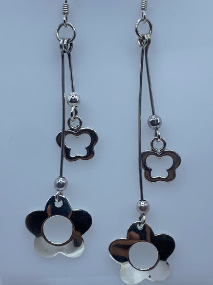 Aretes de plata sobre regla de centímetros marcando 8.4 cm de largo