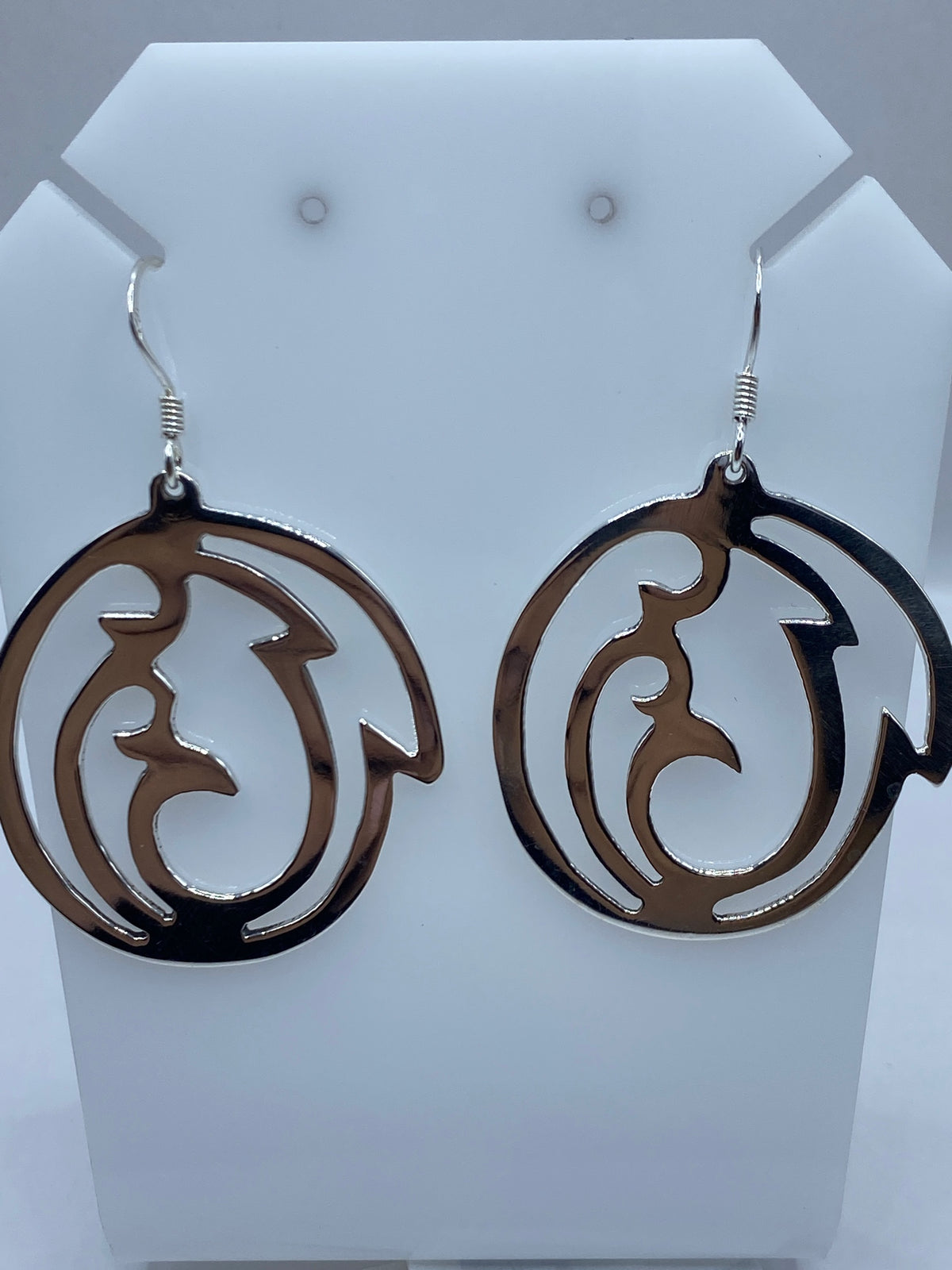 Los dos aretes sobre regla milimétrica mostrando largo de 5.5 cm cada uno