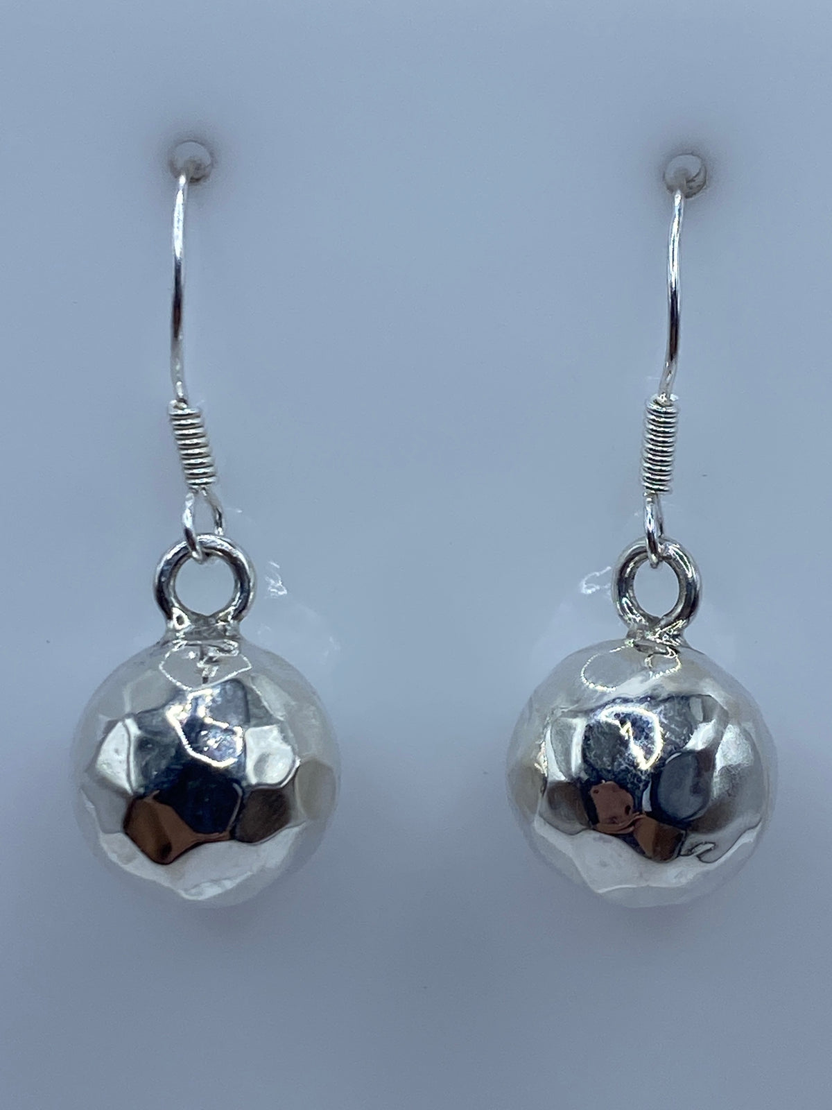 Par de aretes de plata repujados con esferas facetadas, colgando de gancho de plata